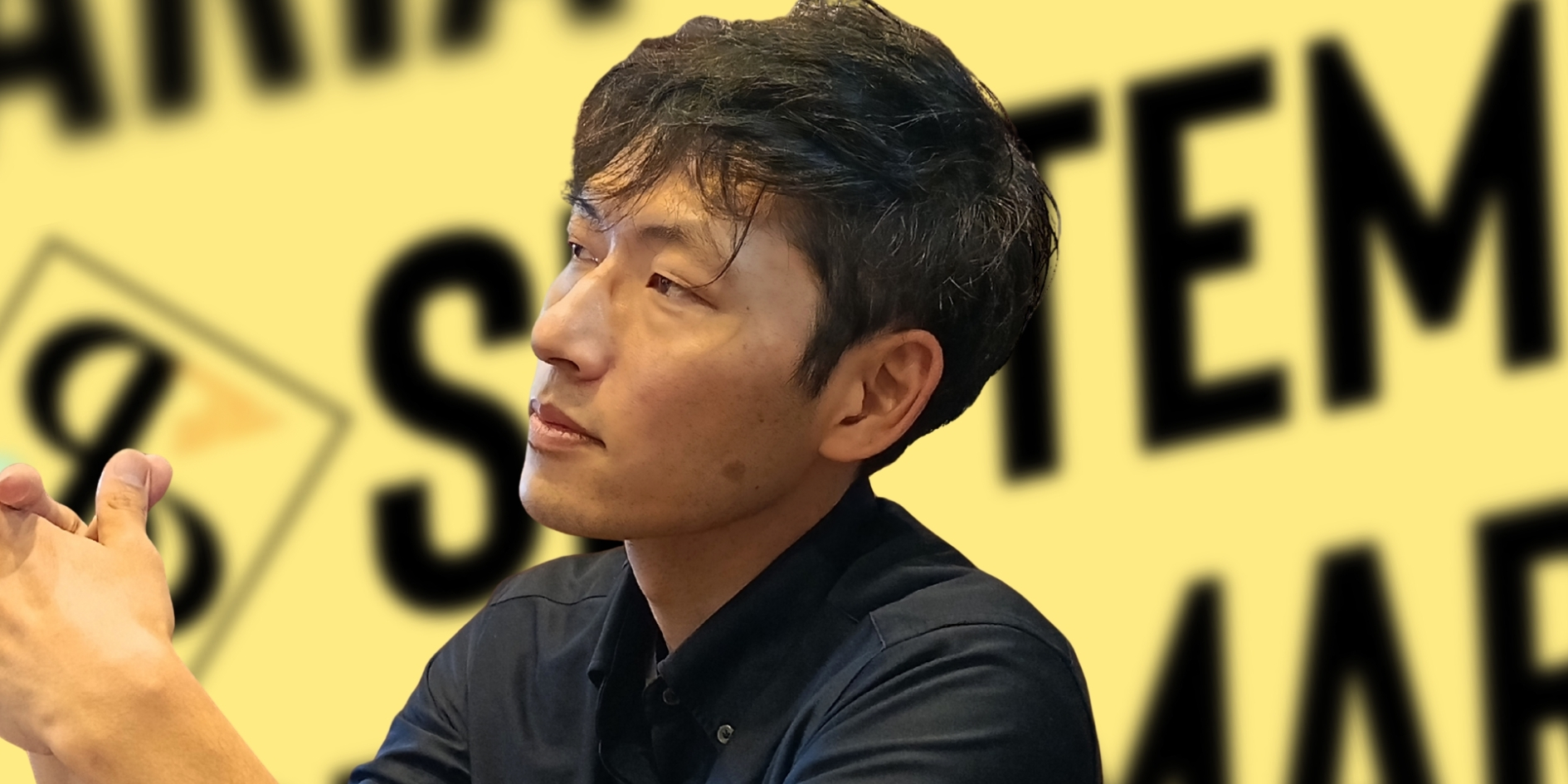黄色のセプテンマリアの背景で撮影した代表取締役・真部裕充のポートレート